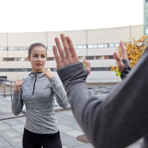 A woman confidently holding her fists up in a defensive stance, illustrating self-defense in martial arts, while a man raises his hands in a 'don't hurt me' gesture