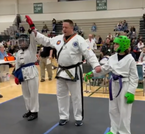 Daniela wins first place in sparring at the 2024 Cornhusker State Games, judge raising her arm in victory — showcasing the benefits of martial arts for kids and teens.
