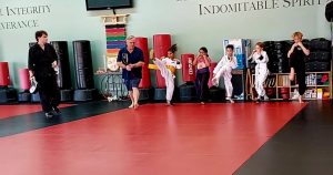 Instructor guides high-achieving students during martial arts training for kids at American Academies of Martial Arts in Bellevue.