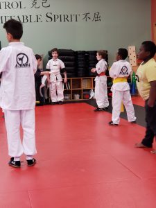 Child receiving a white sash in Kung Fu class, showing one of the best winter activities for kids in Bellevue to build confidence and focus.