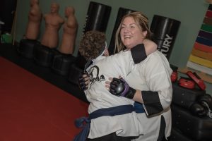 Alison and her son smiling while sparring during Kung Fu class, representing intentional gratitude and family growth through martial arts training.