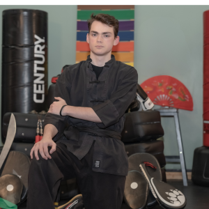 teen martial arts instructor kneeling in uniform showing confidence and discipline in kung fu school”