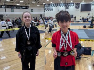 Young martial arts students celebrating with medals at a Kung Fu tournament after competing
