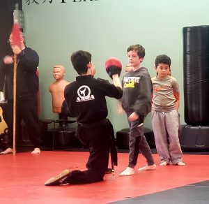 Instructor working pads with a new student during a trial martial arts lesson in Bellevue