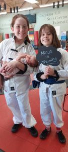Young martial arts students celebrating a new sibling at American Academies of Martial Arts