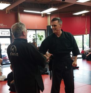 Instructor congratulating a black belt student at American Academies of Martial Arts in Bellevue, Nebraska