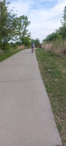 Kid wearing helmet riding bicycle on paved neighborhood trail with friends